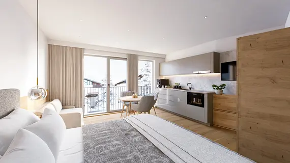 Modernes Hotelzimmer mit gemütlichem Bett, Sitzecke, Kochnische und großen Fenstern mit Blick auf eine verschneite Berglandschaft.