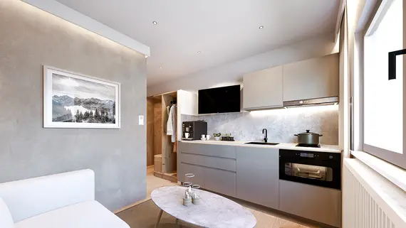 Moderne Küche mit hellen Schränken, Einbaugeräten und einem weißen Sofa; Sonnenlicht fällt durch ein Fenster.