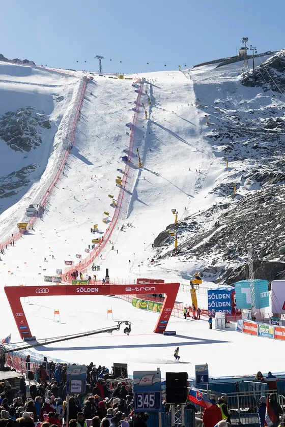 Unten im Bild sieht man die Menschenmenge, die auf den Start des Worldcup-Rennen wartet. In der Mitte des Bildes befindet sich ein gesteckter Lauf und dessen Zieleinlauf auf einer steilen Piste.