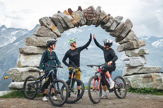 Talstation der Giggijochbahn aus Beton und Metall steht vor grünen Hügeln unter einem blauen Himmel.