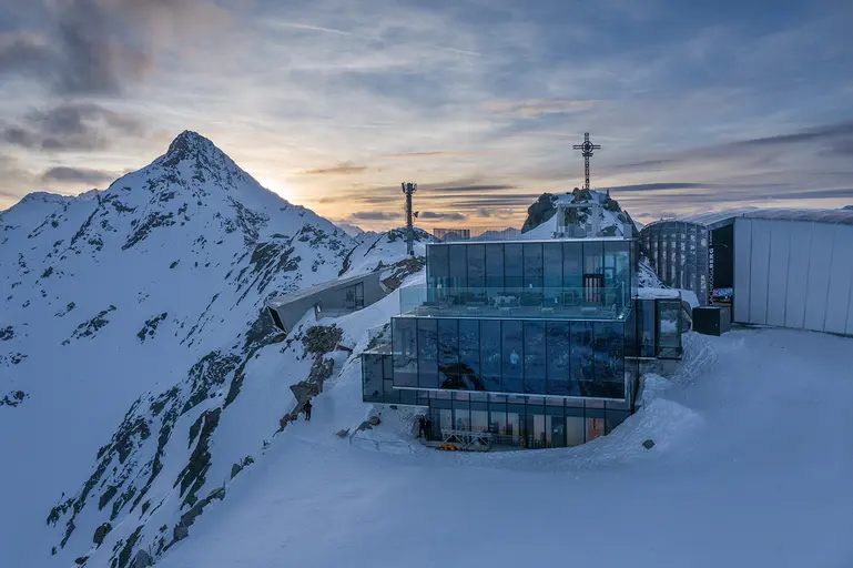 Luftaufnahme vom Ice-Q, ein Restaurant mit Glasfronten, am Gaislachkogl bei Sonnenuntergang. 